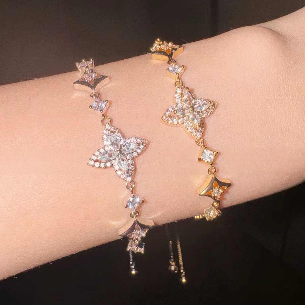 Iris Bloom Zircon Bracelet in gold-tone metal with sparkling clear stones, featuring delicate butterfly and floral charms and an adjustable chain.