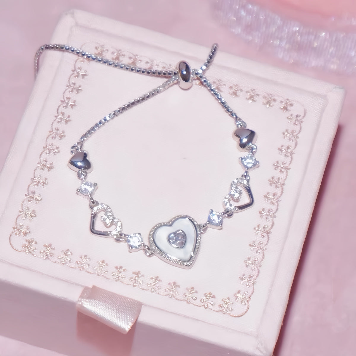 Sweet Holiday Heart Bracelet in silver-tone metal, with glossy heart charms, sparkling clear zircon accents, and an adjustable chain.